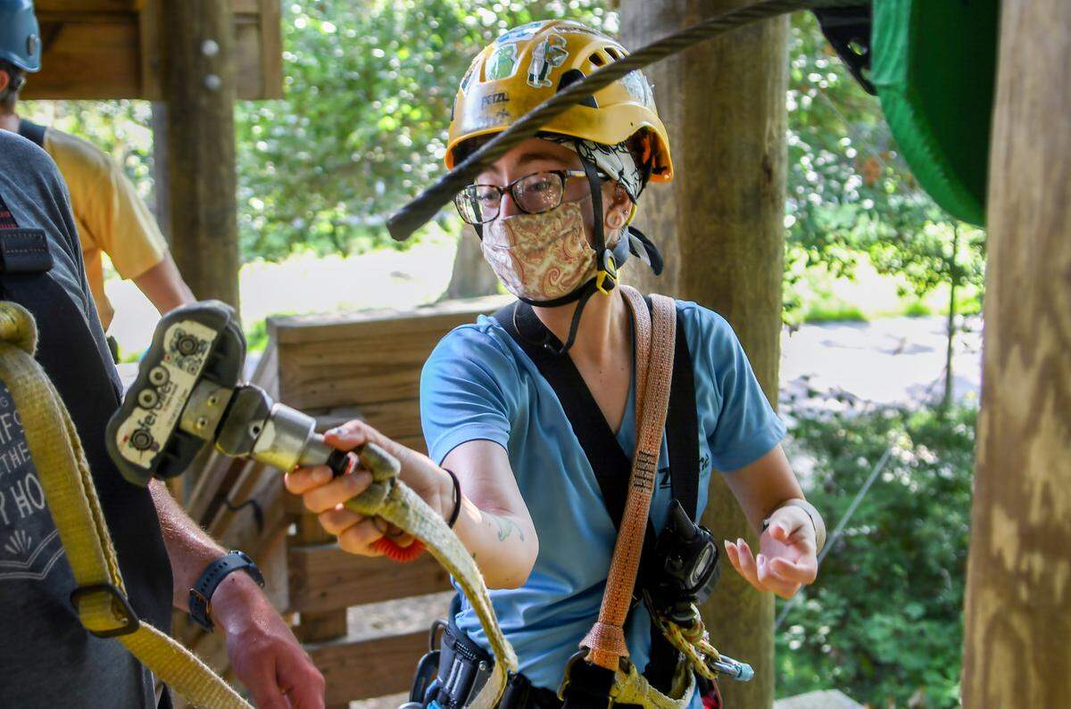 Wearing a face mask and keeping customers six-feet apart, Jordyn Sellers, an Aerial Adventure Challenge Course guide, moves a customer’s SafeRoller Continuous Belay Device on Tuesday, June 30, 2020 at Zip-Line Hilton Head on Hilton Head Island. Before the pandemic, the course could accommodate 50 adventure seekers. Now the company located on Broad Creek allows for only 20 and sanitizes the equipment between groupings.