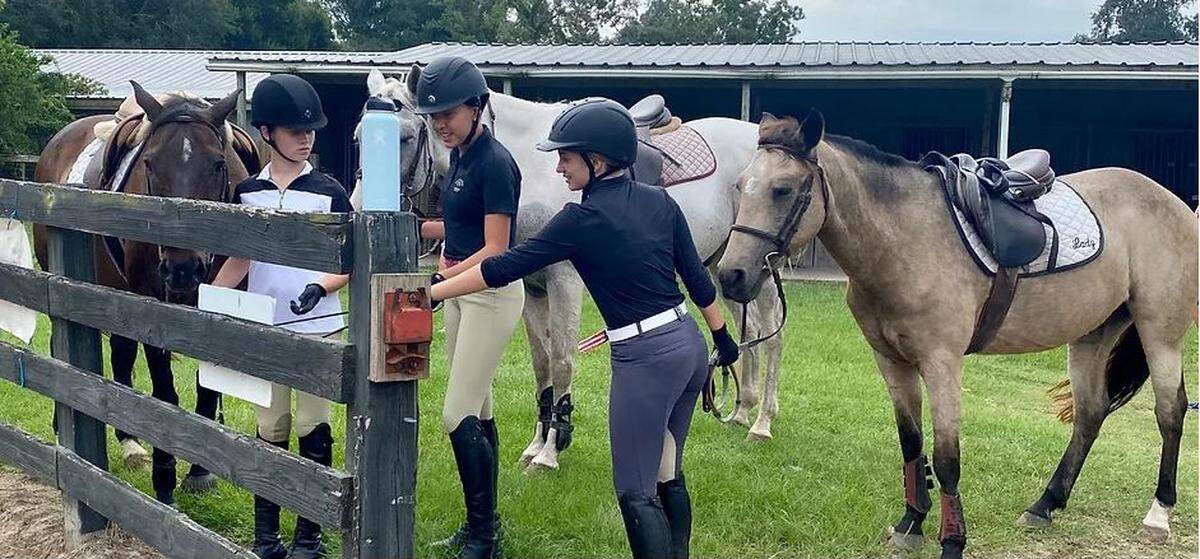 Three riders with their horses at Driftwood Stable. The stable is being forced to relocate as the land has been rezoned for residential use. Photo via the Driftwood Stable website.