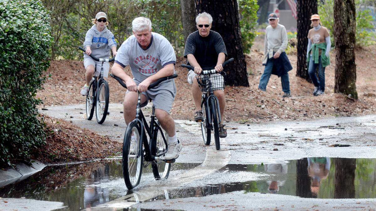 Bicyclists pedal through a puddle on the trail along Hilton Head’s South Forest Beach Drive after heavy rains.