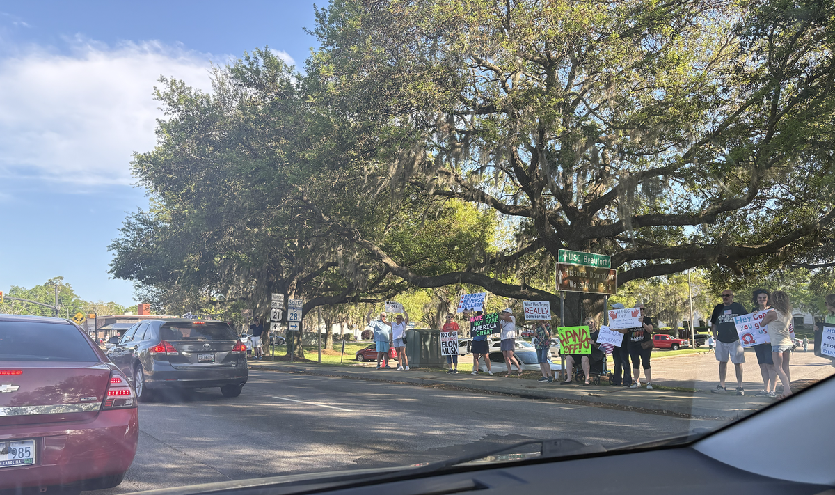Demonstrators holding signs gathered along Boundary Street near its intersection with Ribaut Road in the city of Beaufort on Saturday, April 5, 2025.