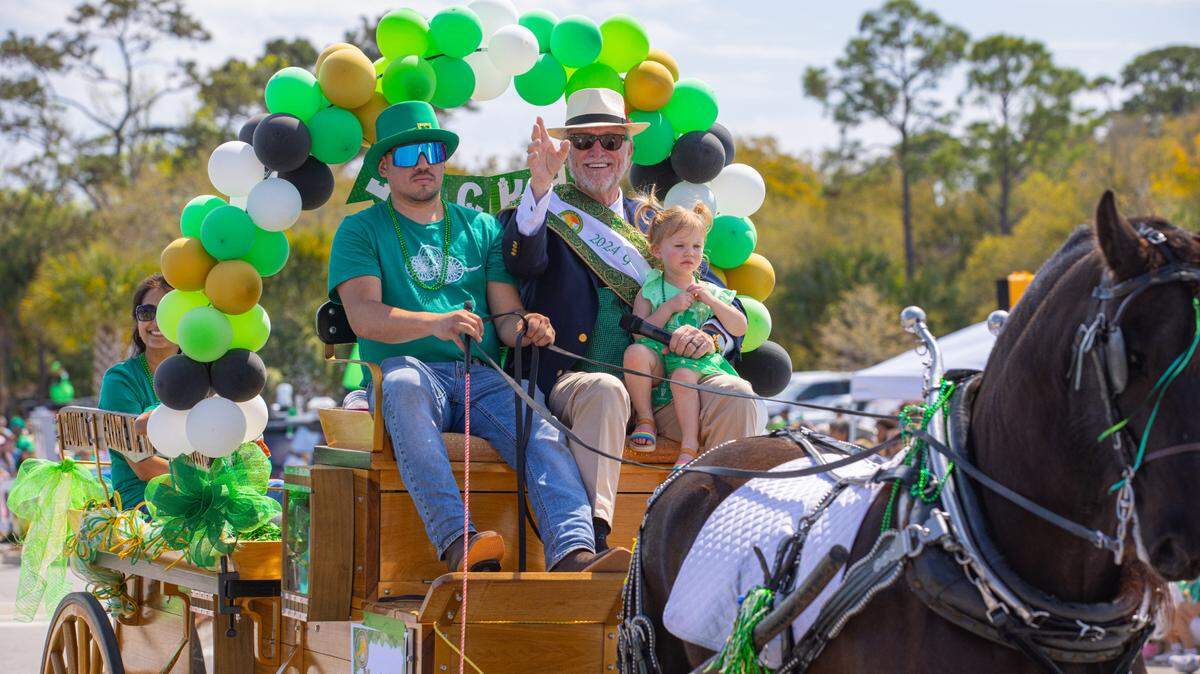 Monty Jett waves to the crowd as grand marshal of the 2024 Hilton Head Island St. Patrick’s Day Parade, holding granddaughter Quinn Jett.