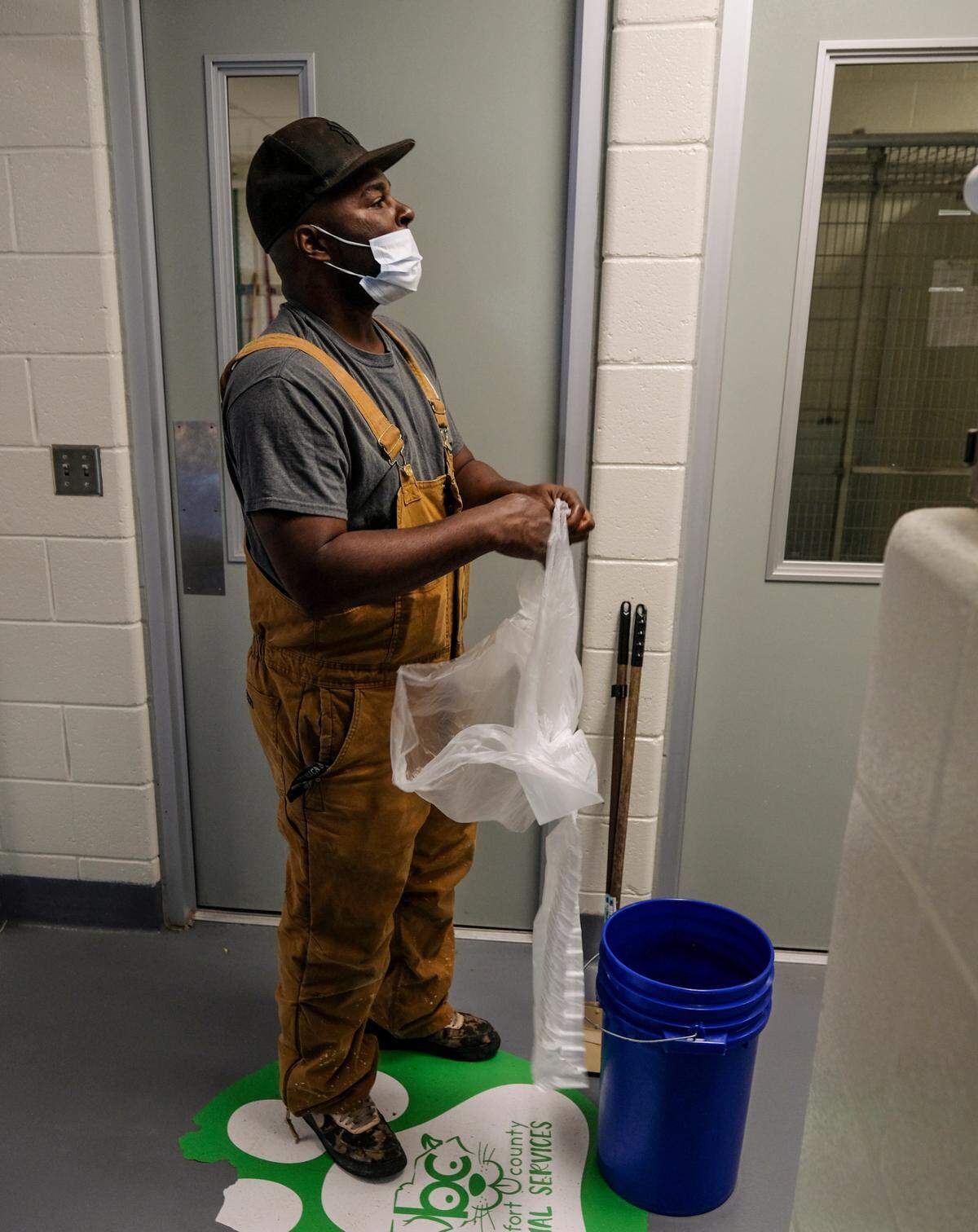 As Trevor Heyward prepares to line a bucket with a garbage bag, an animal services officer yells down the hallway asking for his help in retrieving a captured puppy from her van on Thursday, Feb. 25, 2021 at Beaufort County Animal Services in Okatie. “Things are always busy here.” Heyward said only 18 minutes into his day as he dropped what he was doing to help.