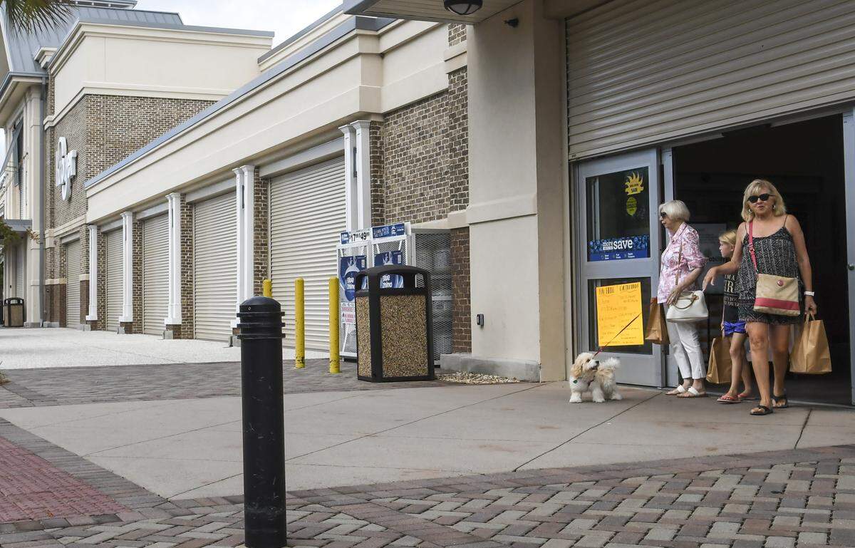 Customers leave the Kroger at Shelter Cove Towne Centre Tuesday morning on Hilton Head Island in preparation for the arrival of Hurricane Dorian. While storm shutters make the store look closed, an entrance at the far end allowed customers entry to shop for groceries.