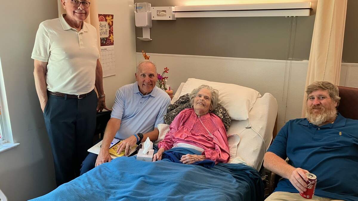 Sally Swan Burke Lauderdale poses in the nursing home on July 4, 2025, with, from left, sons George and David, and grandson Peter.