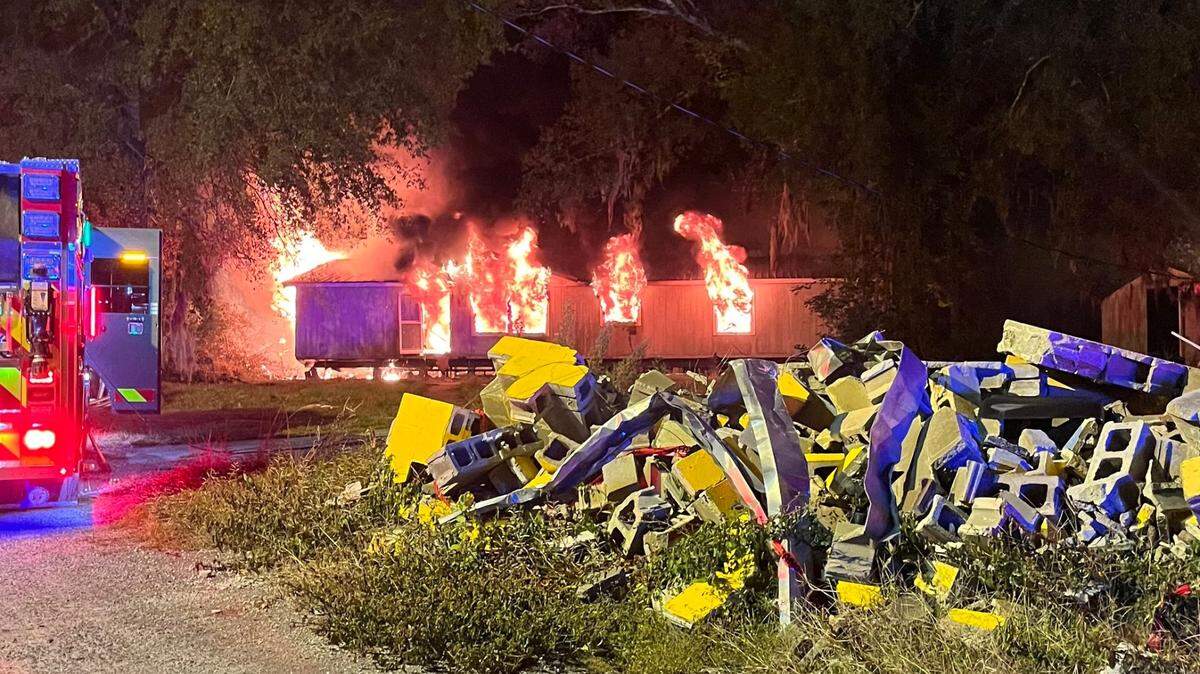 Flames poured out the windows of a mobile home behind the former Papa Joe’s Fireworks after a suspected arson at the business Sunday morning.