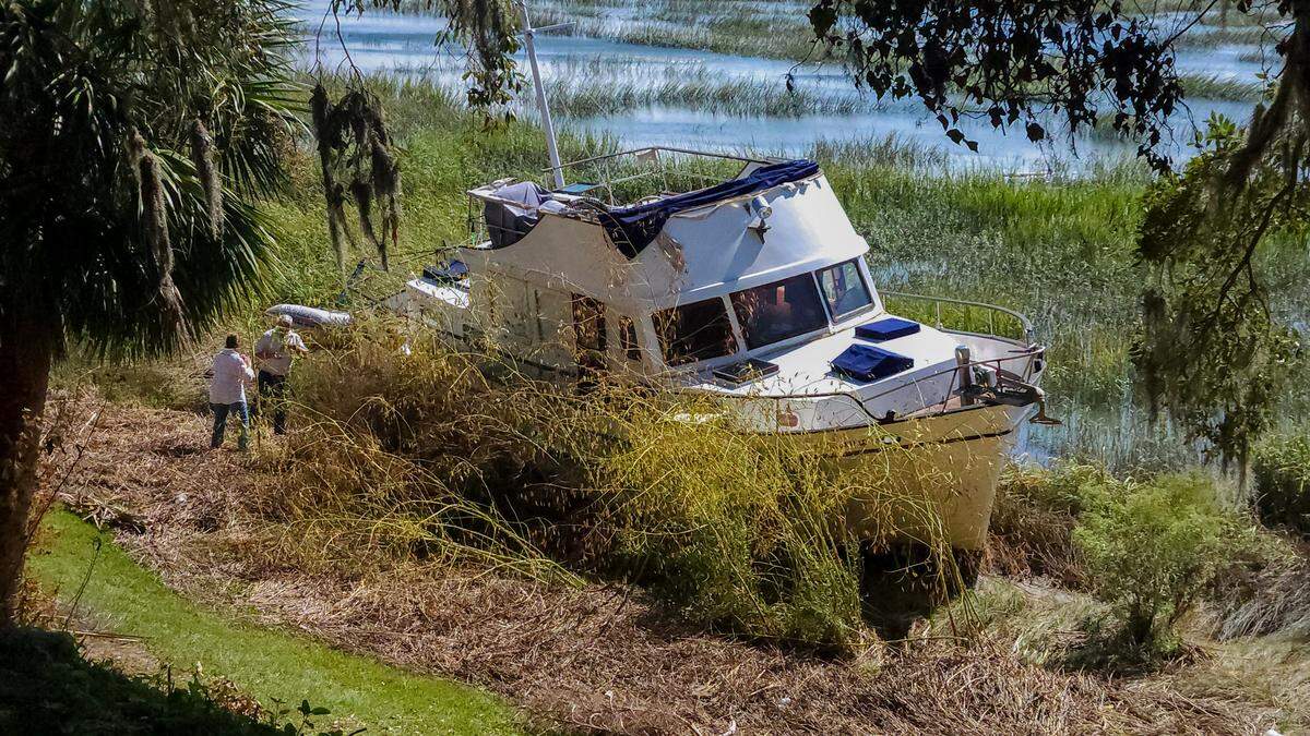 People attempt to board a boat on Oct. 10, 2024 that was washed away from its mooring and landed in the marshes of the Beaufort River in Beaufort. Several boats – likely from the Beaufort Marina – are currently stuck on the river’s bank after Tropical Storm Helene moved through the area on Sept. 27 and less than two weeks later, Hurricane Milton.