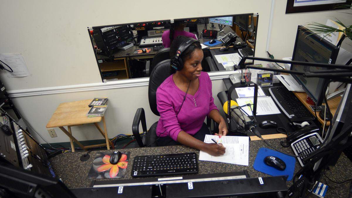 Dee Dee Green, a volunteer DJ at "Gullah People's Network" radio, WKWQ 100.7, keeps busy during a break in the radio show on Thursday afternoon at the radio station's office at Regions Bank on Robert Smalls Parkway in Beaufort.