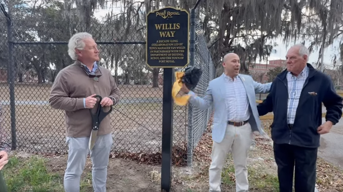 Port Royal Town Councilman Jorge Guerrero, center, unveils a new sign naming a stretch of sidewalk in front of the Naval Hospital after Town Manager Van Willis, left. At right is Greg Shelton, the resident who proposed the idea.