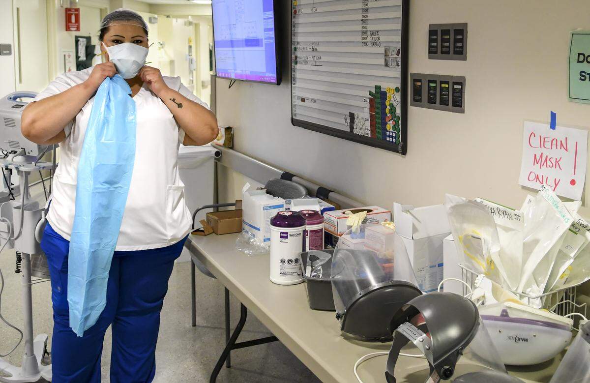 After putting on a N95 face mask, April Simmons-Smith, RN, adds another face mask on April 16, 2020 to protect and preserve the filtering face piece before entering a patient’s room at Beaufort Memorial Hospital.
