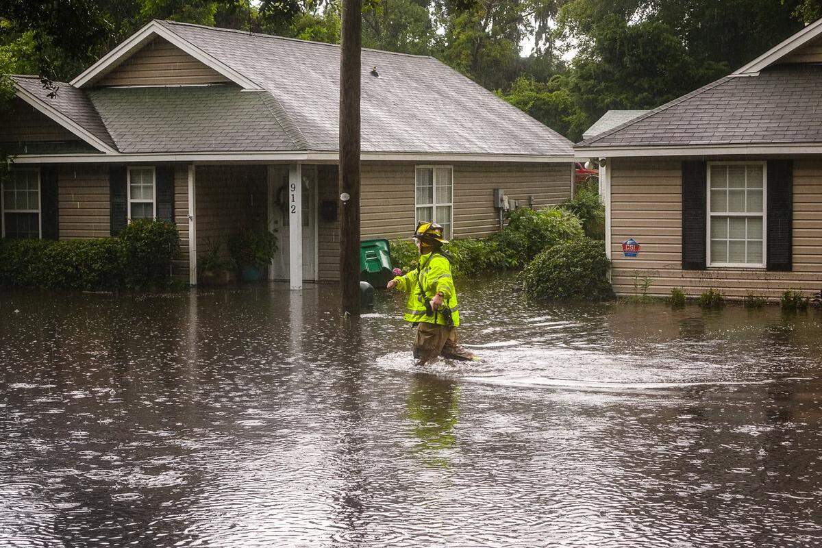 A firefighter wades through flood water on Hamar Street in Beaufort on Thursday, July 19, 2018.