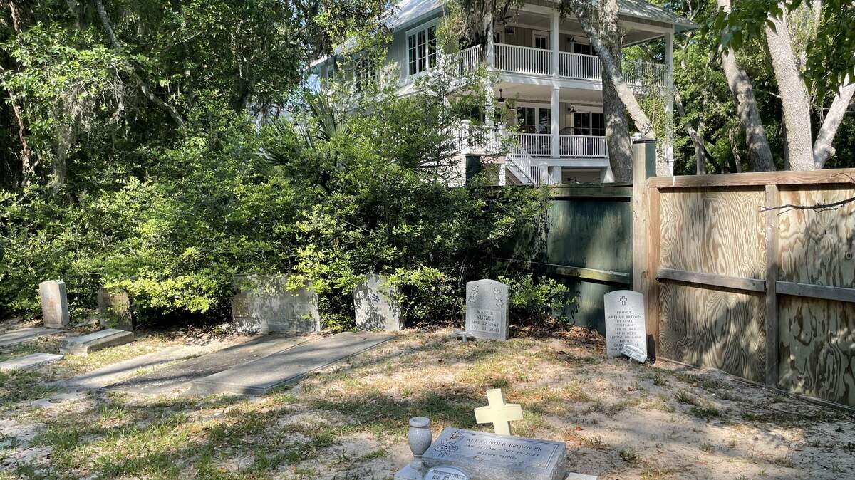 A three-story home, originally constructed as a beachfront wedding venue, towers over a nearby graveyard in the historic Mitchelville area on Hilton Head Island.