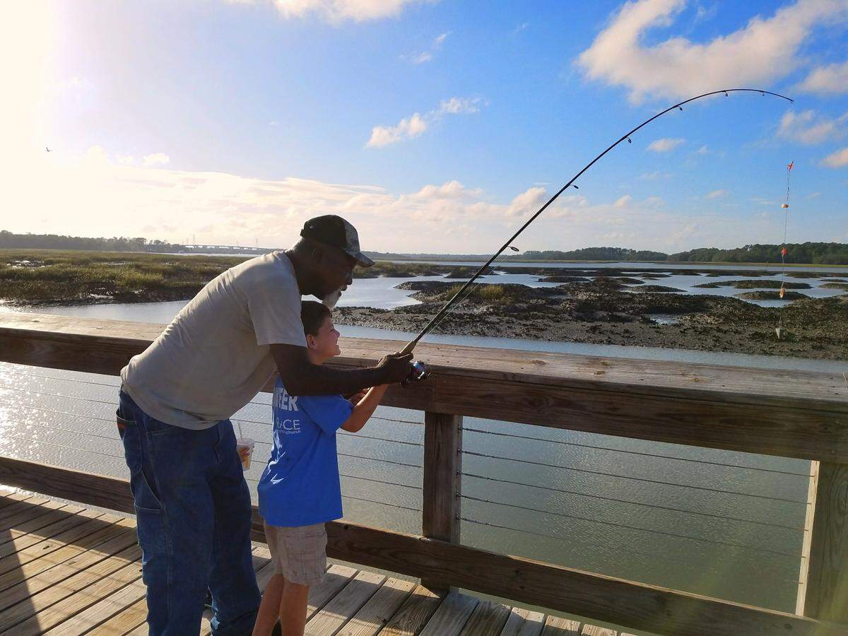 Ben Green helps Graydon Dimaria hold a fishing rod at the old fishing co-op site at Squire Pope Community Park on Hilton Head Island.