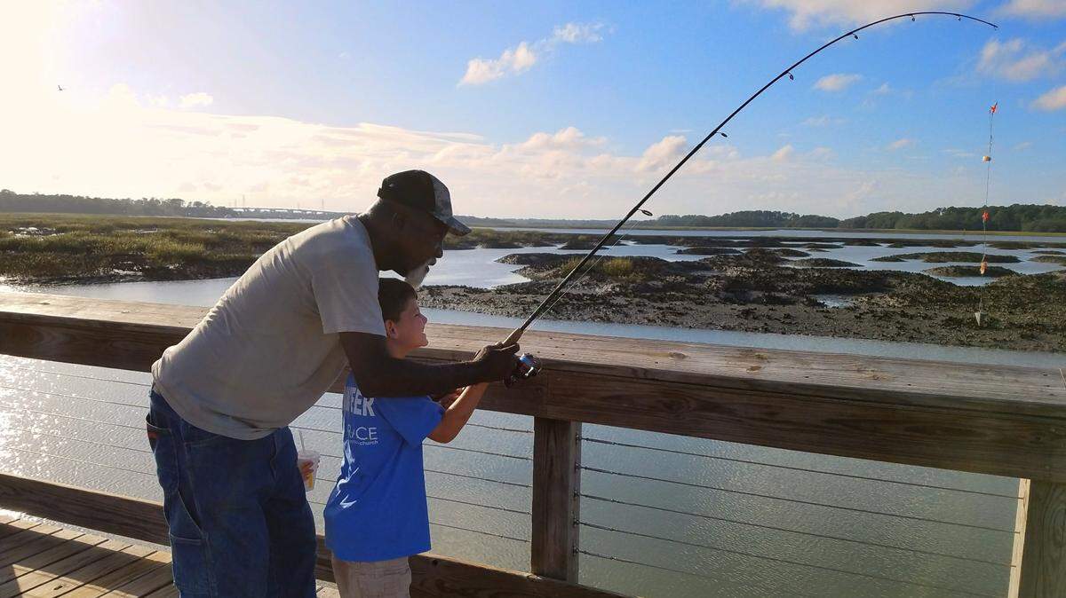 Ben Green helps Graydon Dimaria hold a fishing rod at the old fishing co-op site at Squire Pope Community Park on Hilton Head Island.