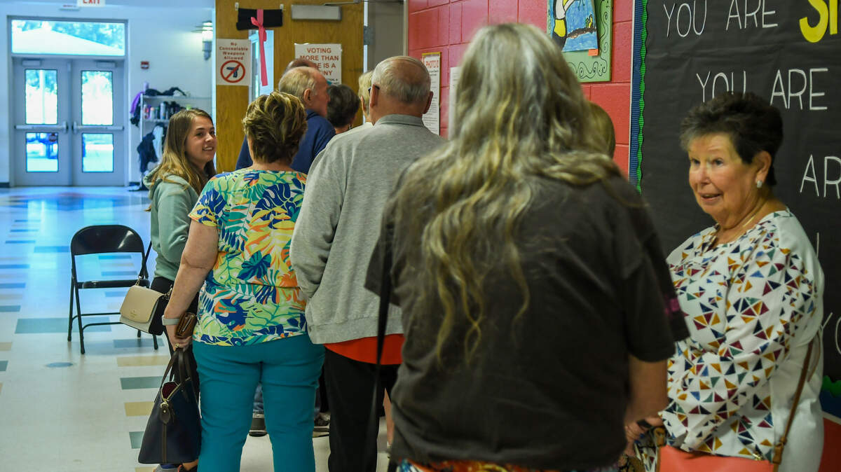 A line of about 20 people talk as they wait in line to cast their votes in the Nov. 7, 2023 General Election for Precincts 2C and 2D at Pritchardville Elementary School in Bluffton. A sign on the door warns that voting more than once is a felony.