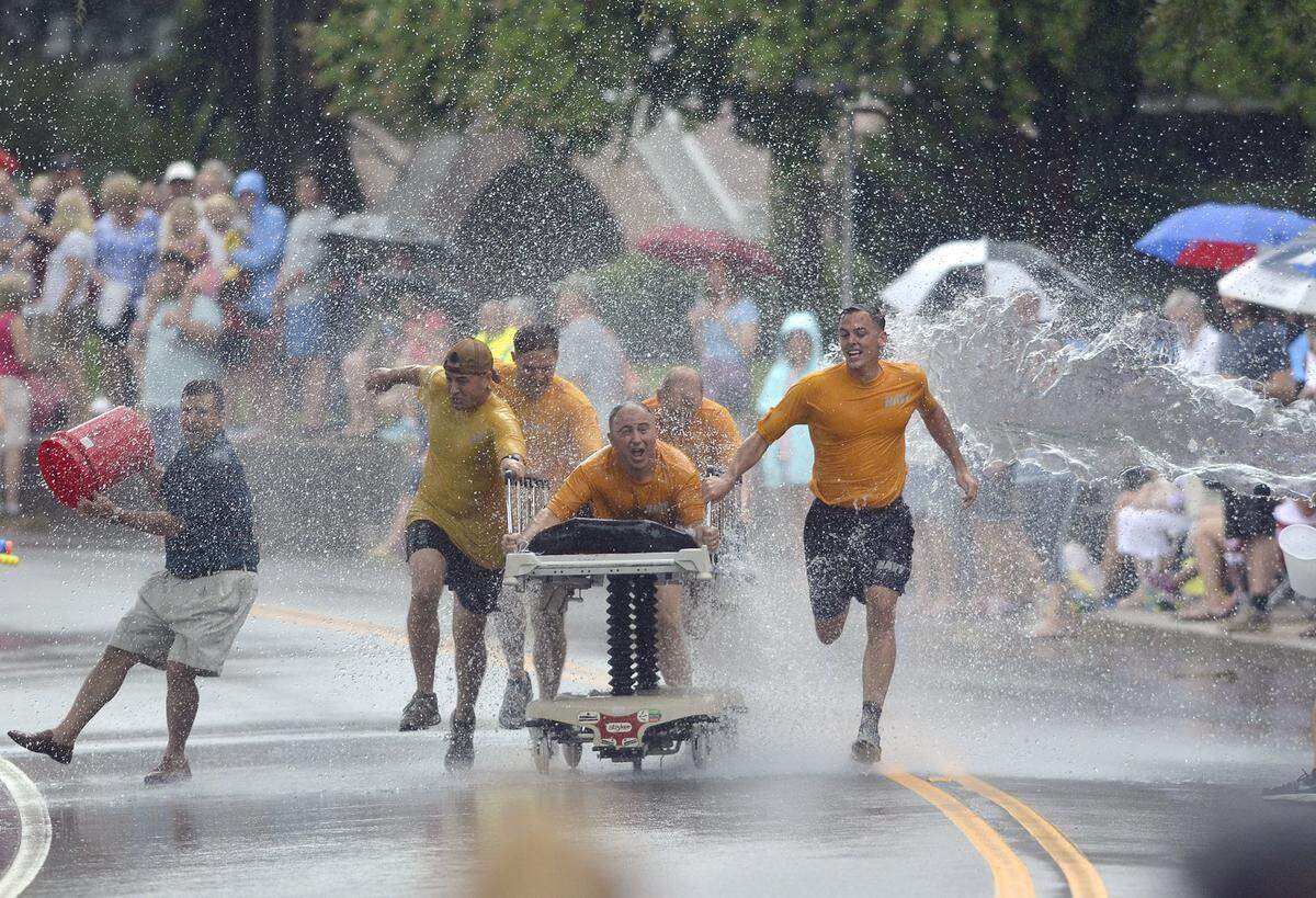 The Lowcountry Seabees pull their bed through a wall of water being thrown on them during a Bed Race during a past Beaufort Water Festival on Bay Street in Downtown Beaufort.