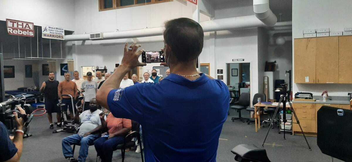 Jim Denton of Carolina Sportscare and Physcial Therapy takes a photo of family and fans of C.J. Cummings who turned out Wednesday to watch Cummings compete in the weightlifting competition at the Tokyo Olympics.