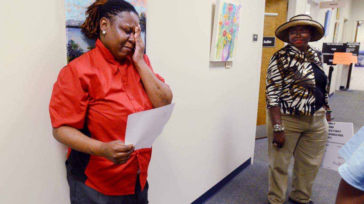 Charima Allen is overcome with emotion in the hallway outside the Beaufort County Treasurer's office as she holds the redemption receipt for the land she and her sister, Claressa Wright, own on St. Helena Island. The land had been foreclosed on by the county for unpaid taxes, but was recovered by the sisters on Friday with the aid of the Pan-African Family Empowerment & Land Network. Looking on is Theresa White, president and CEO of the network, which paid the sisters' back taxes of $941.54.