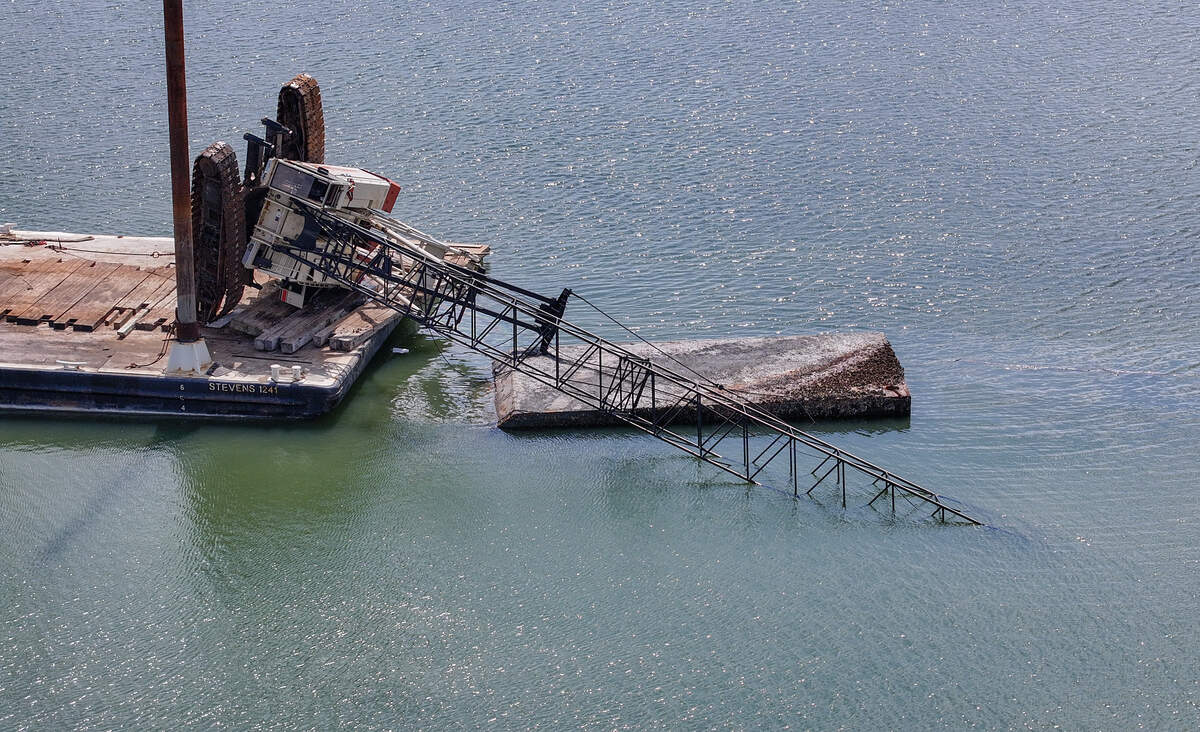 A crane sits precariously tipped over on a barge as photographed on June 30, 2026, in Mackay Creek near the bridges to Hilton Head Island. According to on-scene members of the United States Coast Guard, operators of the crane likely misjudged the counterweight as they were trying to remove the smaller barge as seen in the foreground.