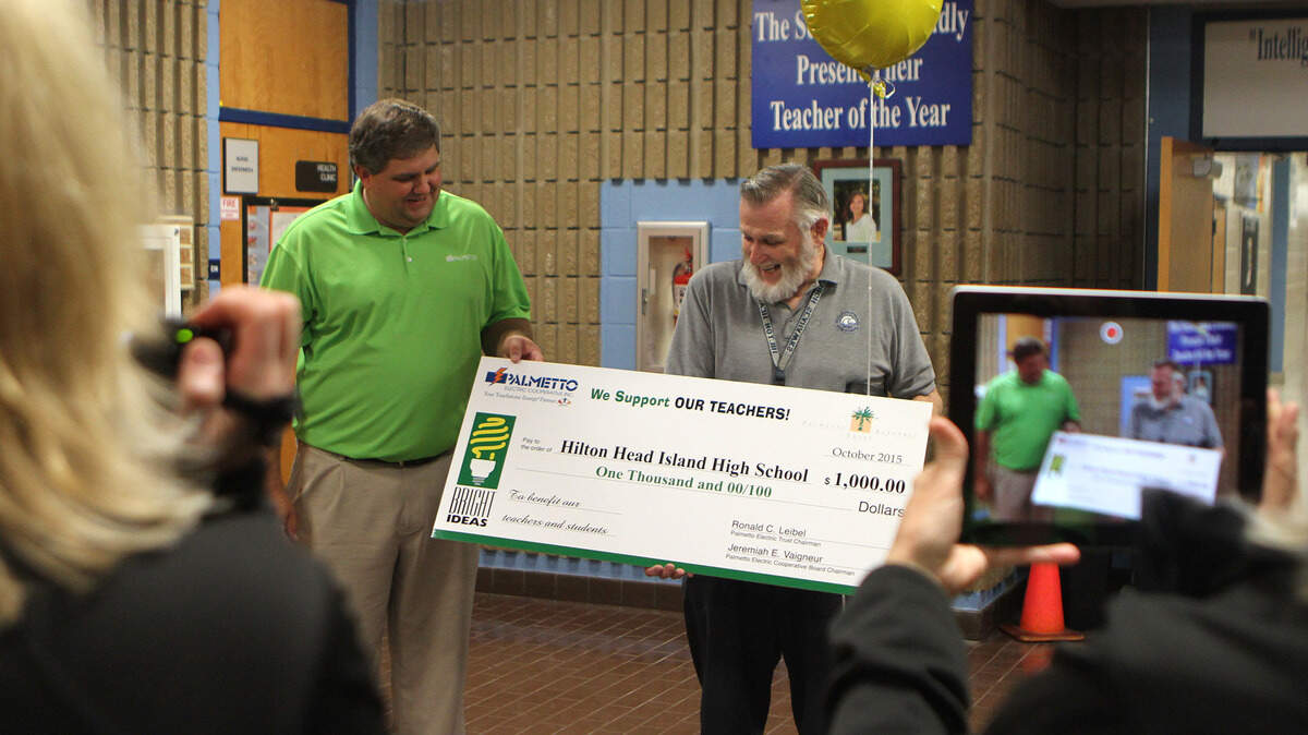 John Quindlen, right, smiles as Tray Hunter, vice president of marketing and public relations for Palmetto Electric Cooperative Inc., hands him a big check for $1,000 the morning of Oct. 26, 2015, at Hilton Head Island High School.
