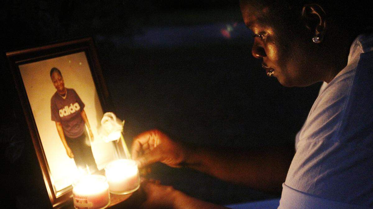 Shontelle Black, grandniece of murder victim Polly Ann Mitchell, places a rose next to Mitchell's photograph during a May 15, 2014, vigil in Bluffton.