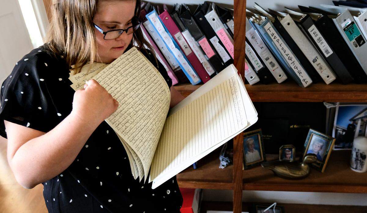Caroline Campbell, pages through chapters of her handwritten, word-for-word transcriptions of the New American Standard version of the Bible on Thursday, May 27, 2021 in her Beaufort home. Campbell, who has Down syndrome, started with one verse in January 2012 and on Sunday June 9, she’ll finish transcribing the entire Bible with the last sentence while standing in front of her congregation at Community Bible Church, almost a decade later.