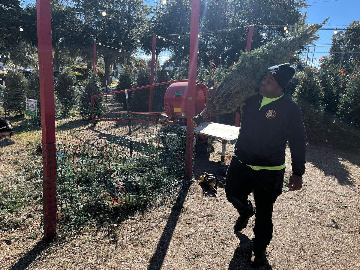 Each year, Devin Mitchell, a Beaufort firefighter, helps out at the Beech Mountain Farms Christmas tree lot on Lady’s Island. “The camaraderie,” he says, when asked why. “The happiness of the people.”