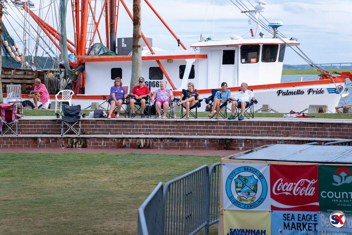 With a shrimp boat behind them, residents enjoy the Beaufort Water Festival at Waterfront Park Tuesday. The Lowcountry Supper is Thursday evening.