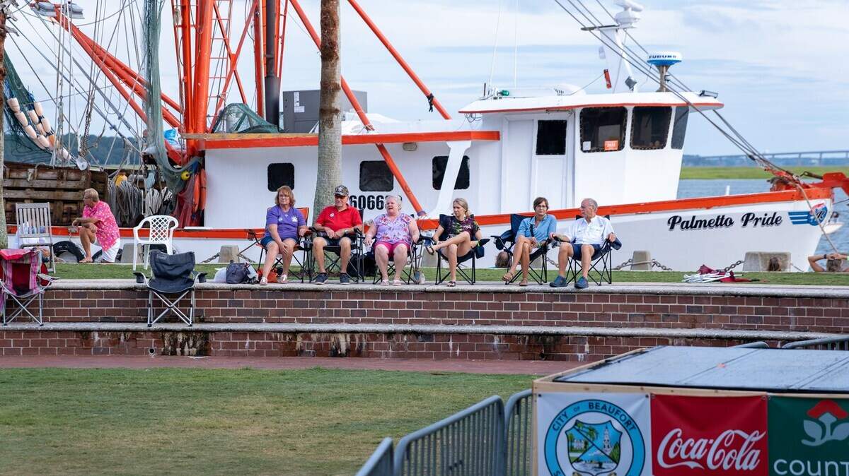 With a shrimp boat behind them, residents enjoy the Beaufort Water Festival at Waterfront Park Tuesday. The Lowcountry Supper is Thursday evening.