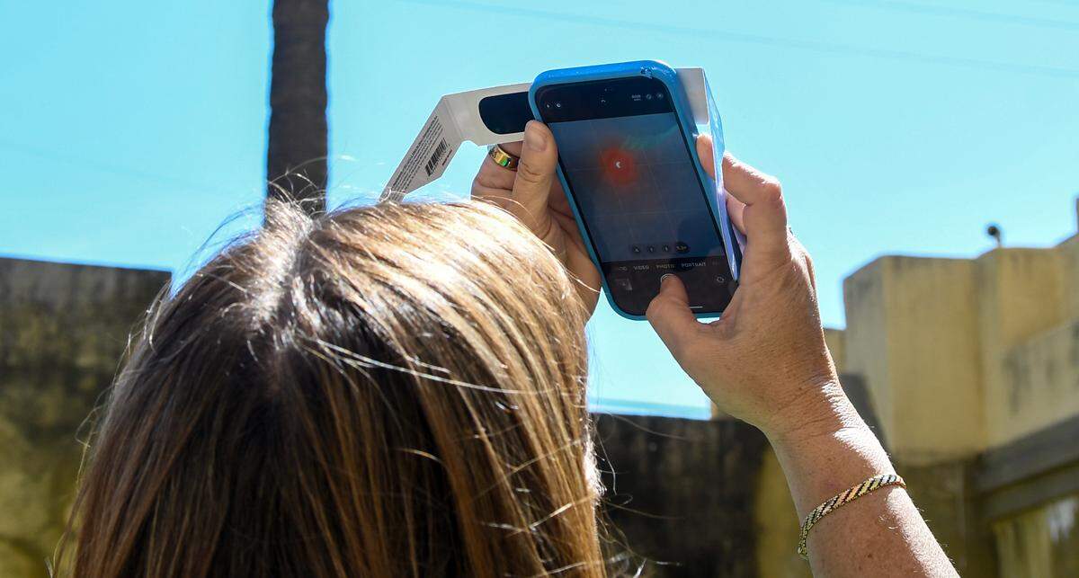 A woman uses her eclipse glasses to cover her smartphone’s camera as she takes a photos of Monday’s eclipse in the courtyard of The Arsenal, home of the Beaufort History Museum. The Beaufort County Library system offered free eclipse viewing glasses at all of its branches for eclipse watch parties.
