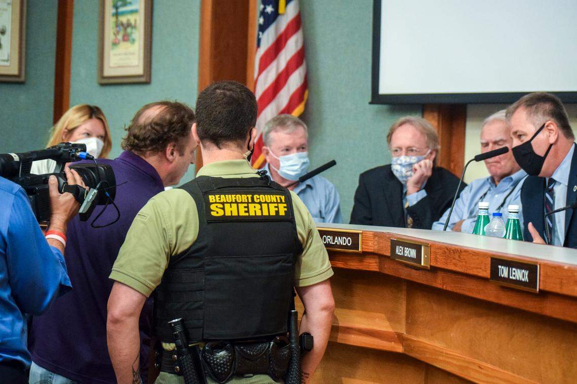 A Beaufort County Sheriff’s Office deputy watches members of the Hilton Head Island Town Council as a protester approaches on Aug. 17, 2021. A television reporter also films the incident.