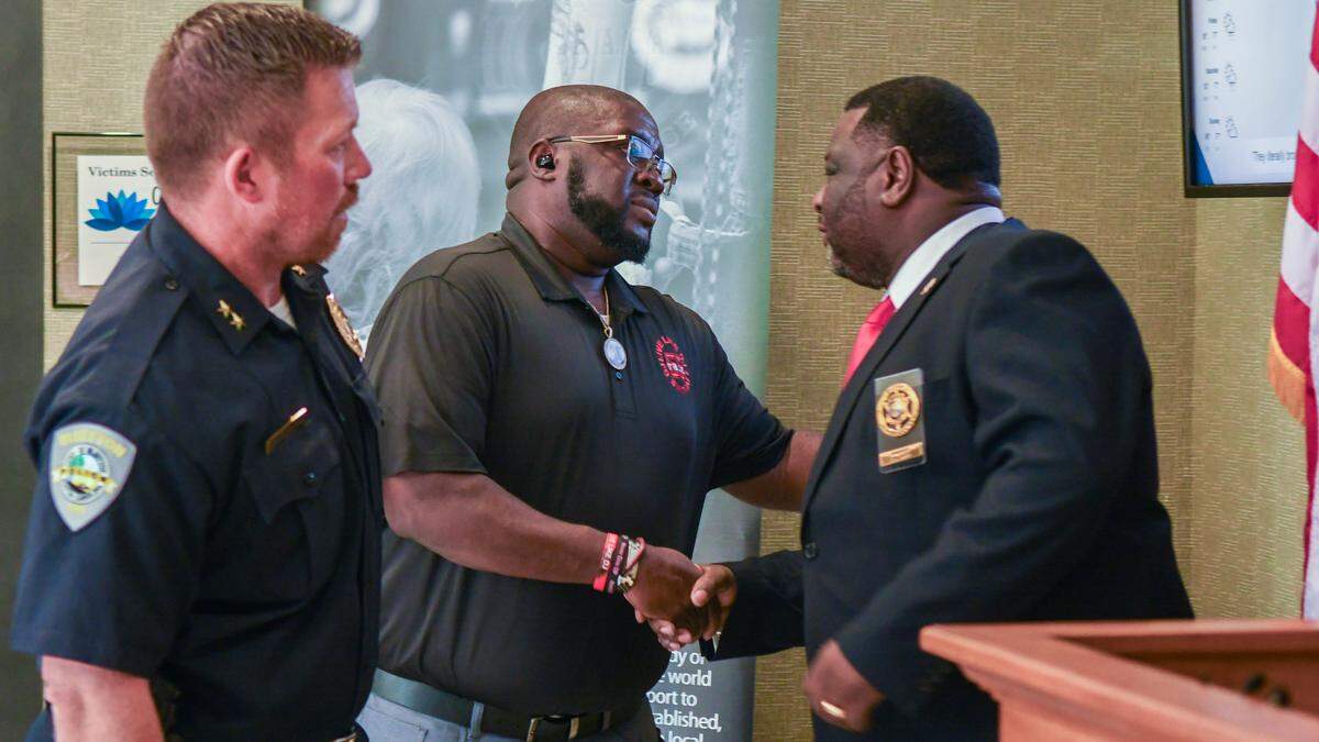 Dwon Fields, center, father of the late Bluffton teen Dwon “D.J.” Fields,&nbsp;shakes hands with Jasper County Sheriff Donald Hipp after 14th Circuit Solicitor Duffie Stone announced on July 6, 2023 the arrest of a man alleged to have been involved in the killing of Fields’ son in 2021. Stone says the man, 15 years old at the time of the murder, will have to be petitioned from Family Court to face a murder charge and two attempted murder charges.