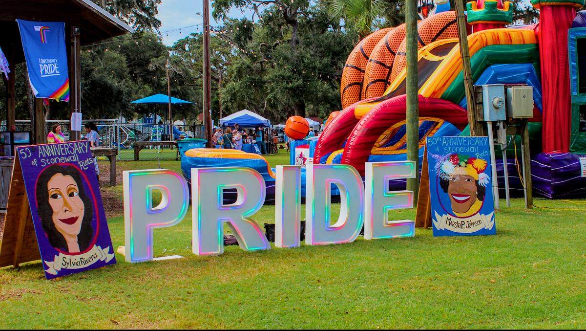 A light-up pride sign faces 14th street at Live Oaks Park in Port Royal. To its left and right are signs commemorating transgender rights activists Sylvia Rivera and Marsha P. Johnson.