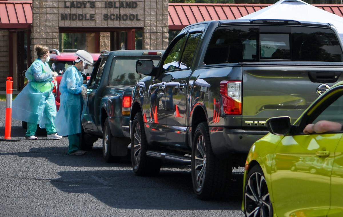 Workers quickly administer free COVID-19 tests in one of two lanes of vehicles on Wednesday, July 15, 2020 at Lady’s Island Middle School.