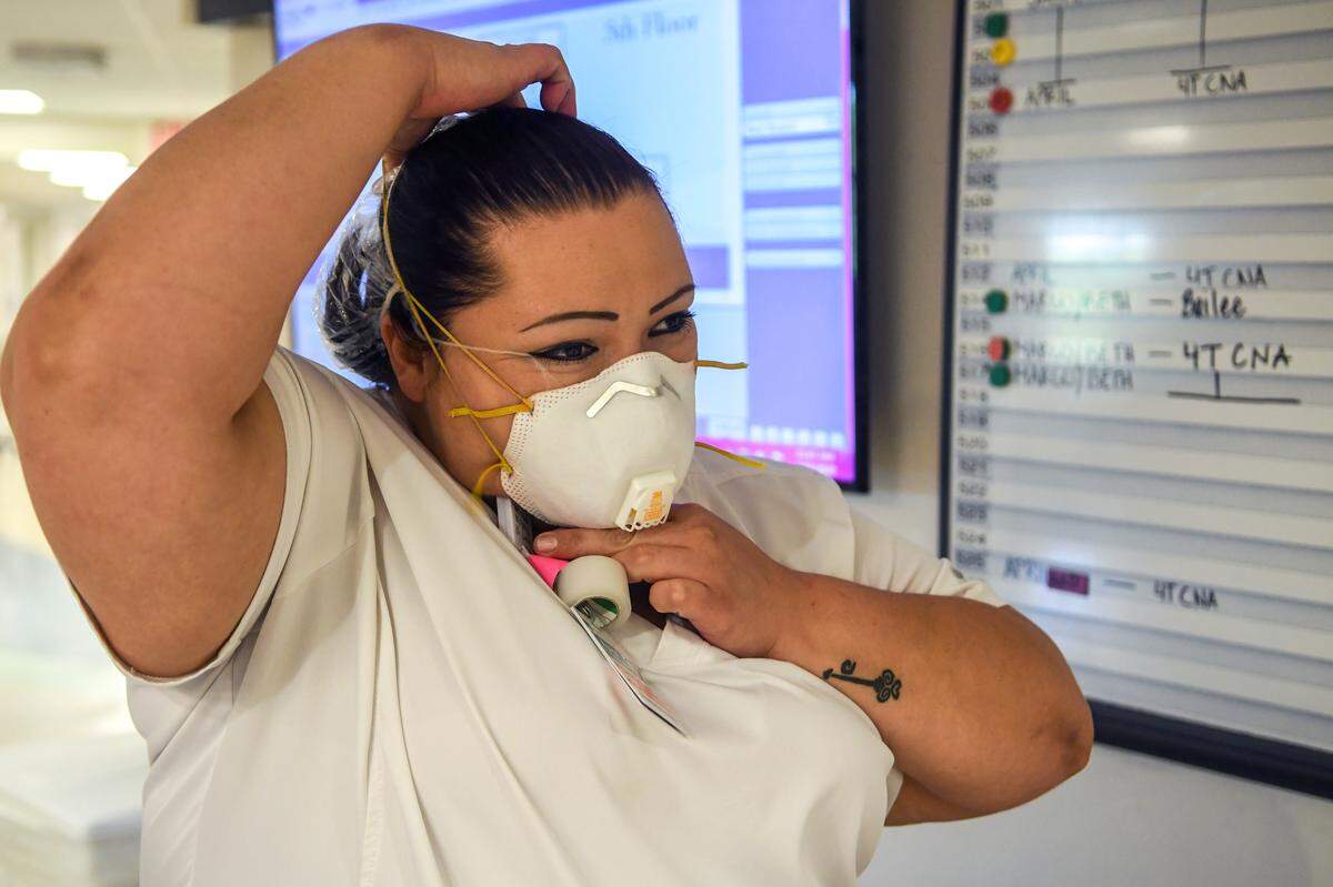 April Simmons-Smith, RN, starts the routine of putting on personal protective equipment that includes a N95 respirator face mask on April 16, 2020 before entering a patient’s room at Beaufort Memorial Hospital.