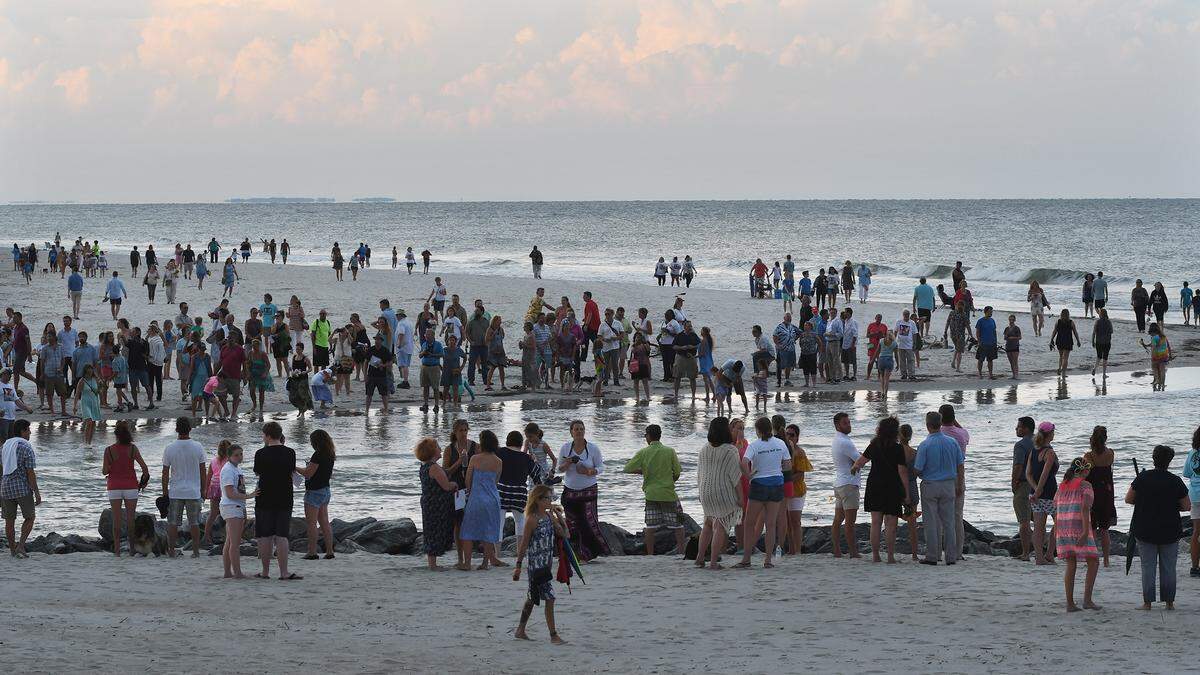 People gather on both sides of The Folly tidal creek after Wednesday evening's celebration of life service for Charli Bobinchuck, who was struck by a motorist and killed just before 11 p.m. Thursday, June 21. The service was held at Chaplin Community Park, where flowers were distributed to attendees to carry to The Folly, a favorite place of Bobinchuck's.