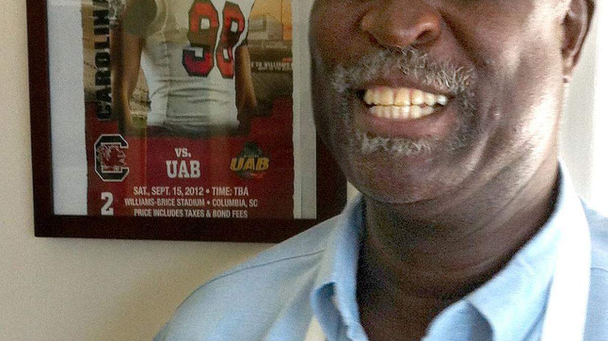 Larry Taylor poses by a photo of his son, University of South Carolina defensive end Devin Taylor, hanging at his LT’s restaurant on Lady’s Island.