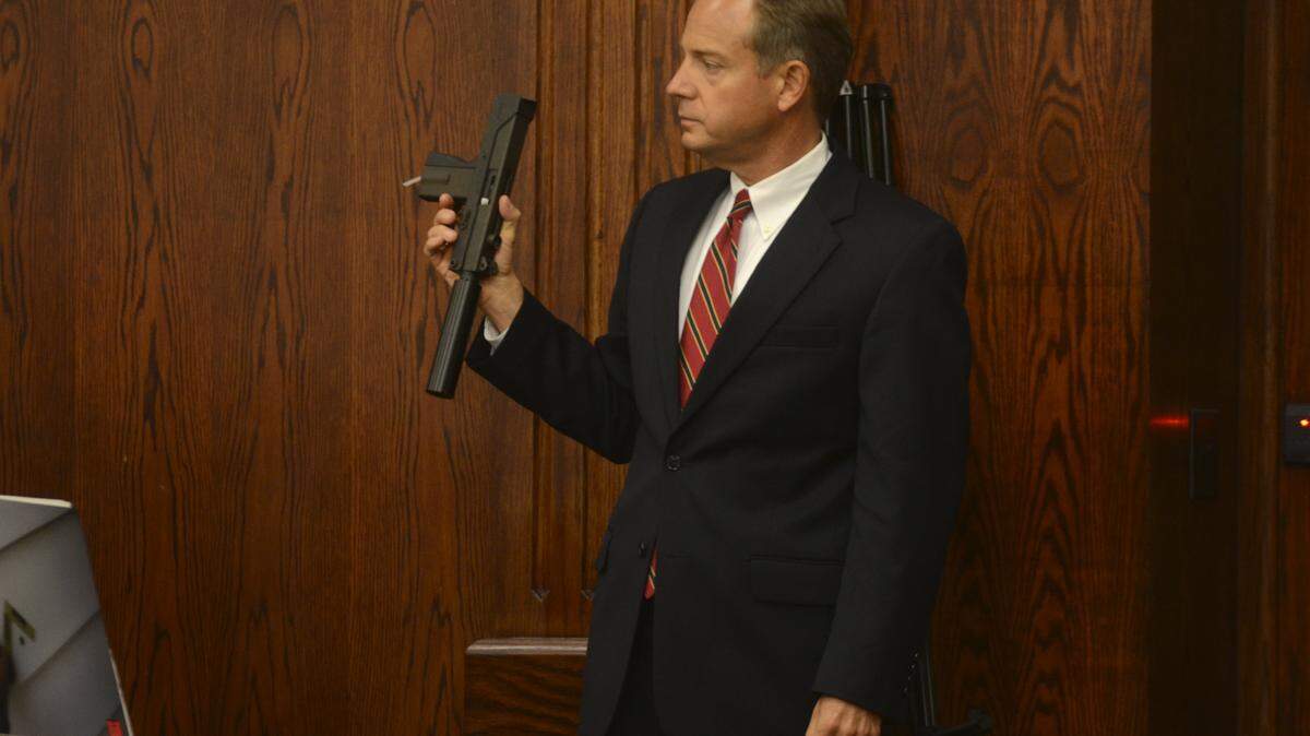 14th Circuit Solicitor Duffie Stone holds the semi-automatic pistol belonging to Aaron Young Sr. and Aaron Young Jr. after Dan DeFreese, a firearms expert, testified that the Young's gun did not kill Khalil Singleton on the third day of Tyrone Robinson's murder trial on Sept. 17, 2014 at the Beaufort County Courthouse.  Robinson is charged with murder in the 2012 shooting death of 8-year-old Khalil Singleton on Hilton Head Island.