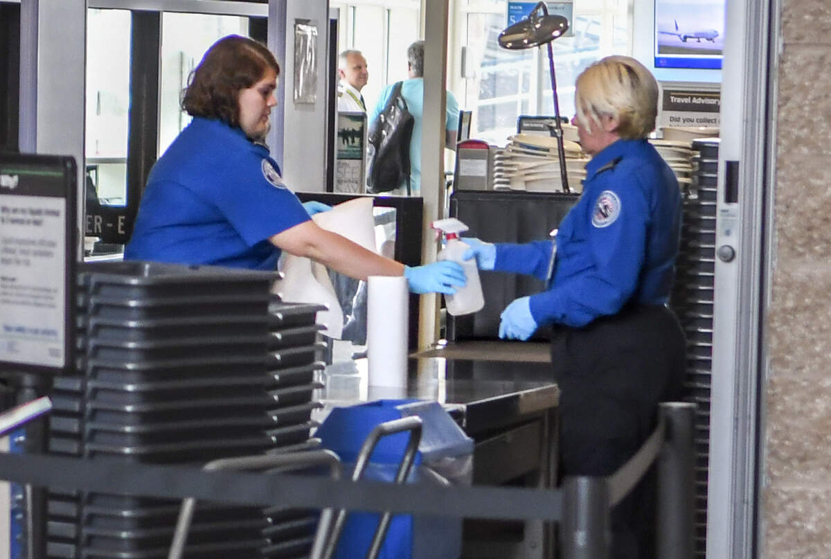 In hopes of stemming the spread of the coronavirus virus, Transportation Security Administration employees wipe down bins and counter tops after ticket holders moved through security on Friday morning, March 27, 2020 at Hilton Head Airport.