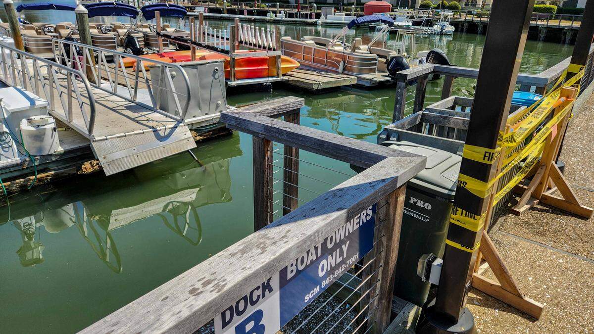 Garbage cans, yellow caution tape and a warning sign posted by the Town of Hilton Head Island warn users on March 20, 2025, of an aluminum gangway that separated from the land to Dock B at Shelter Cove Marina. On March 12, 2025, 15 to 20 people were on the gangway when it collapsed, sending eight people to the hospital with minor injuries, officials said.