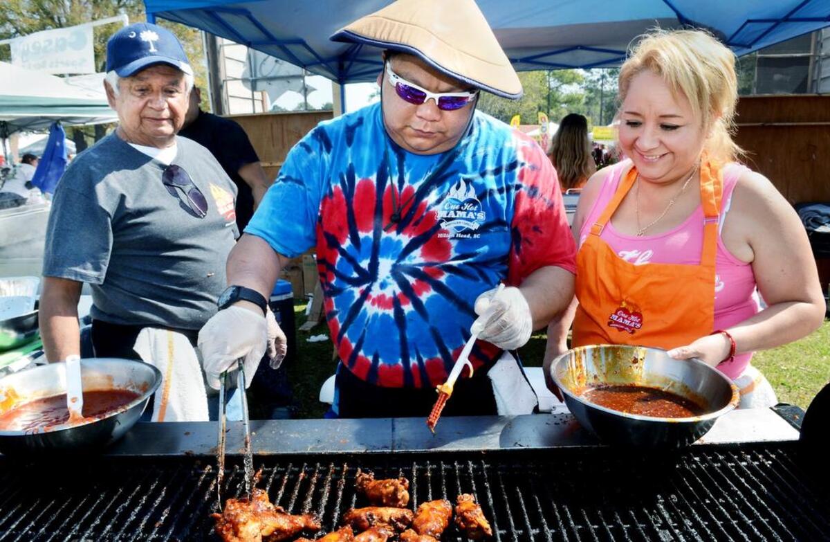 Don Mendoza, left, and Velia Chavez look on as One Hot Mama’s kitchen manager Andrew Doty grills a batch of chicken wings during the 2015 Hilton Head Island WingFest at Hilton Head’s Shelter Cove Community Park.