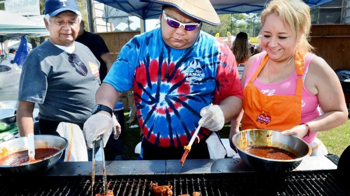 Don Mendoza, left, and Velia Chavez look on as One Hot Mama’s kitchen manager Andrew Doty grills a batch of chicken wings during the 2015 Hilton Head Island WingFest at Hilton Head’s Shelter Cove Community Park.