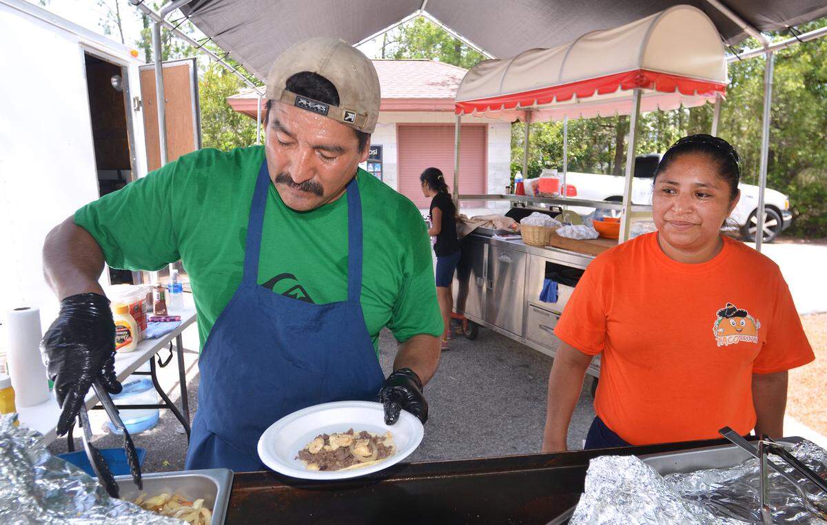 Porfirio Cardelas builds a taco in 2017 while his wife, Susana, looks on at their Taco Brown food truck -- which is really more of a trailer-based food stand -- at the parking lot of Hilton Head's Chaplin Community Park, which doubles as the parking lot for nearby Burkes Beach. Taco Brown, along with It's Only Fair, were one of four food trucks licensed by the town to operate at two Hilton Head Island beaches in 2017.
