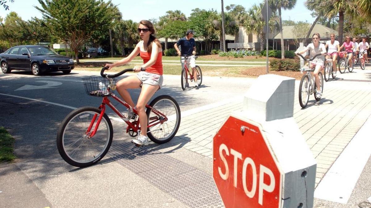 In this file photo, a family of tourists crosses Pope Avenue near the Coligny Beach Park traffic circle while one biker stops traffic on Hilton Head Island.