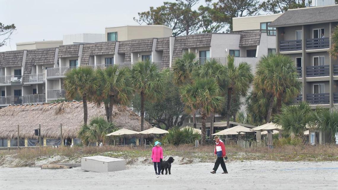 Beachgoers stroll past The Beach House: A Holiday Inn Resort, foreground, and Ocean One condominiums at Coligny Beach on Dec. 7, 2016.