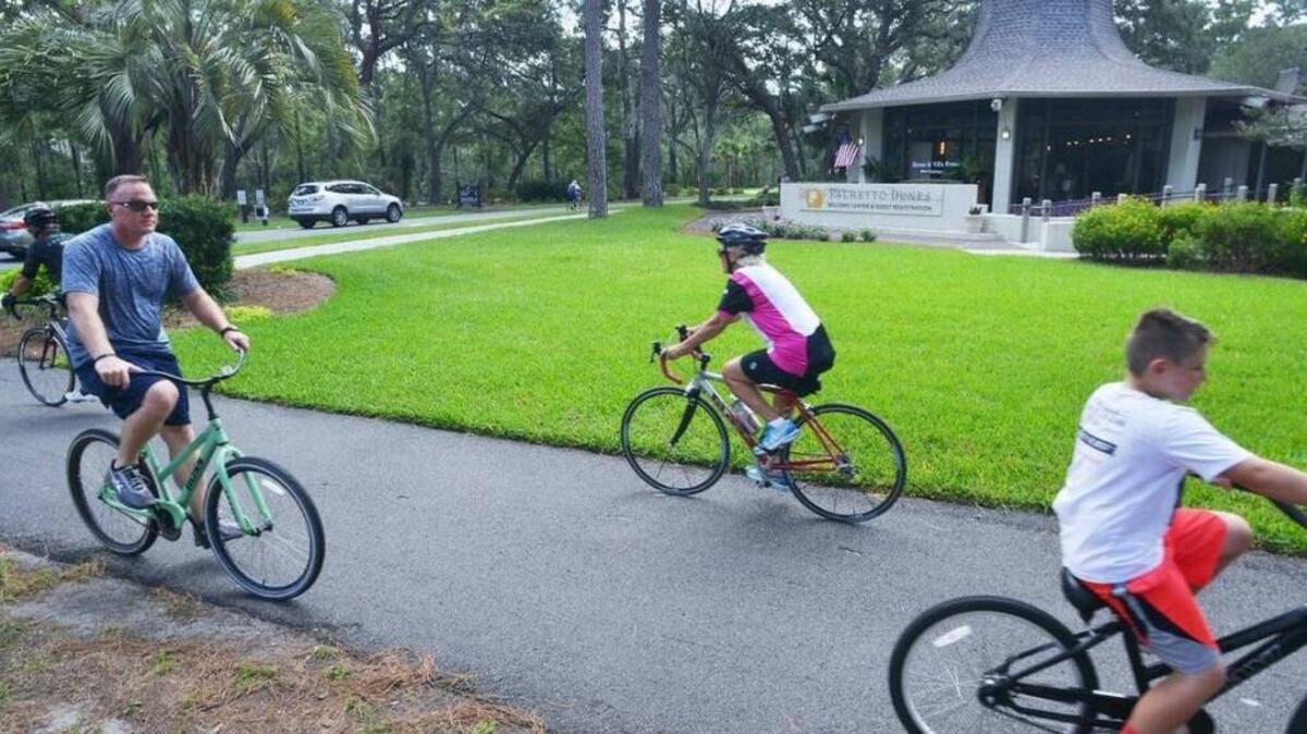 Bicyclists pedal past the Palmetto Dunes Resort's Welcome Center.