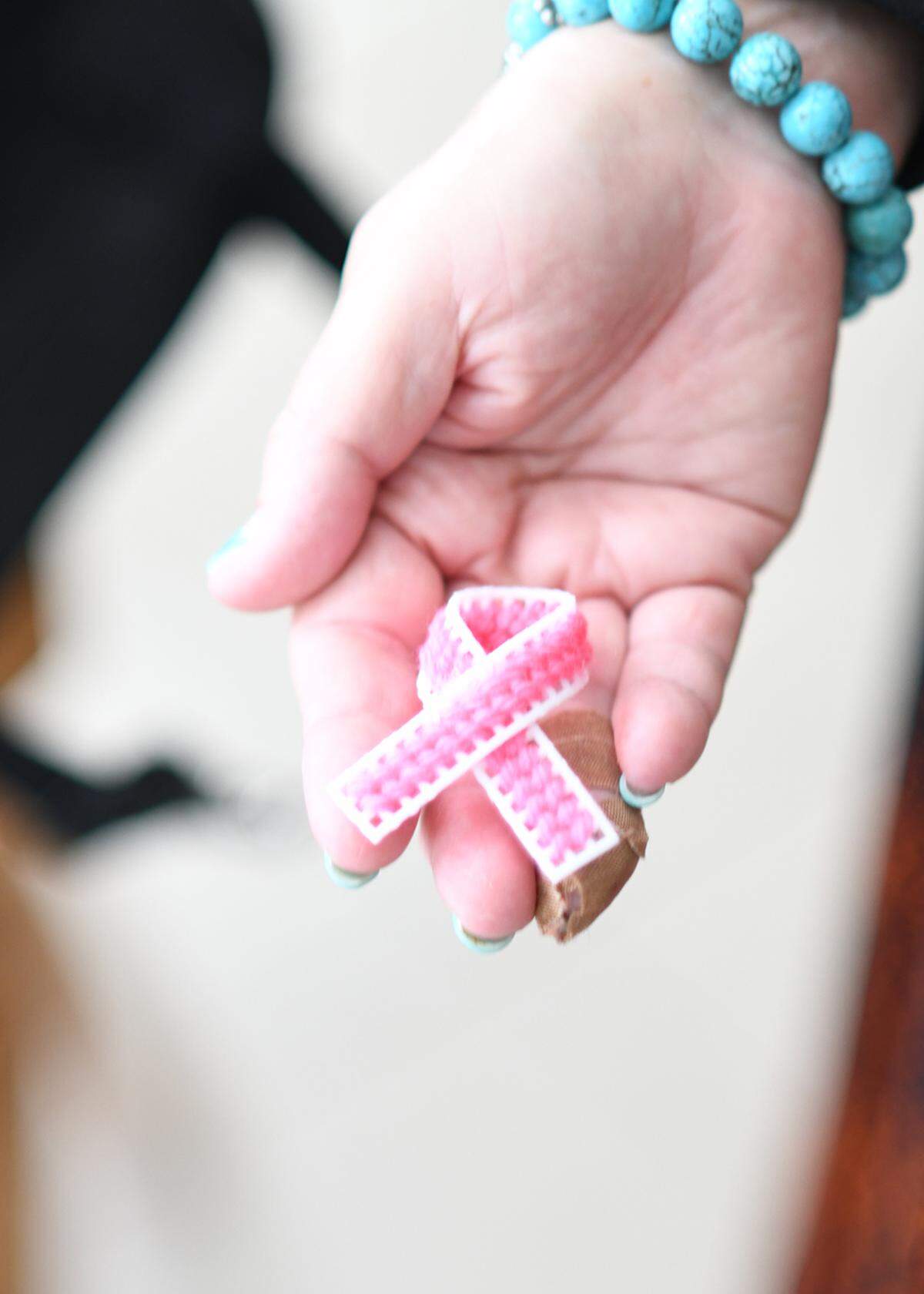 Judy Ferguson of Sun City holds onto a pink ribbon made by needlepoint. She was given this gift while undergoing cancer treatments.