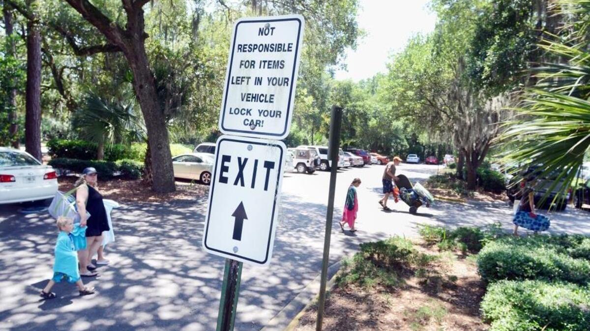 Beachgoers walk across the Coligny Beach parking lot on Hilton Head Island. Parking in the lot is currently free, but town officials are talking about the possibility of charging for beach parking across the island.