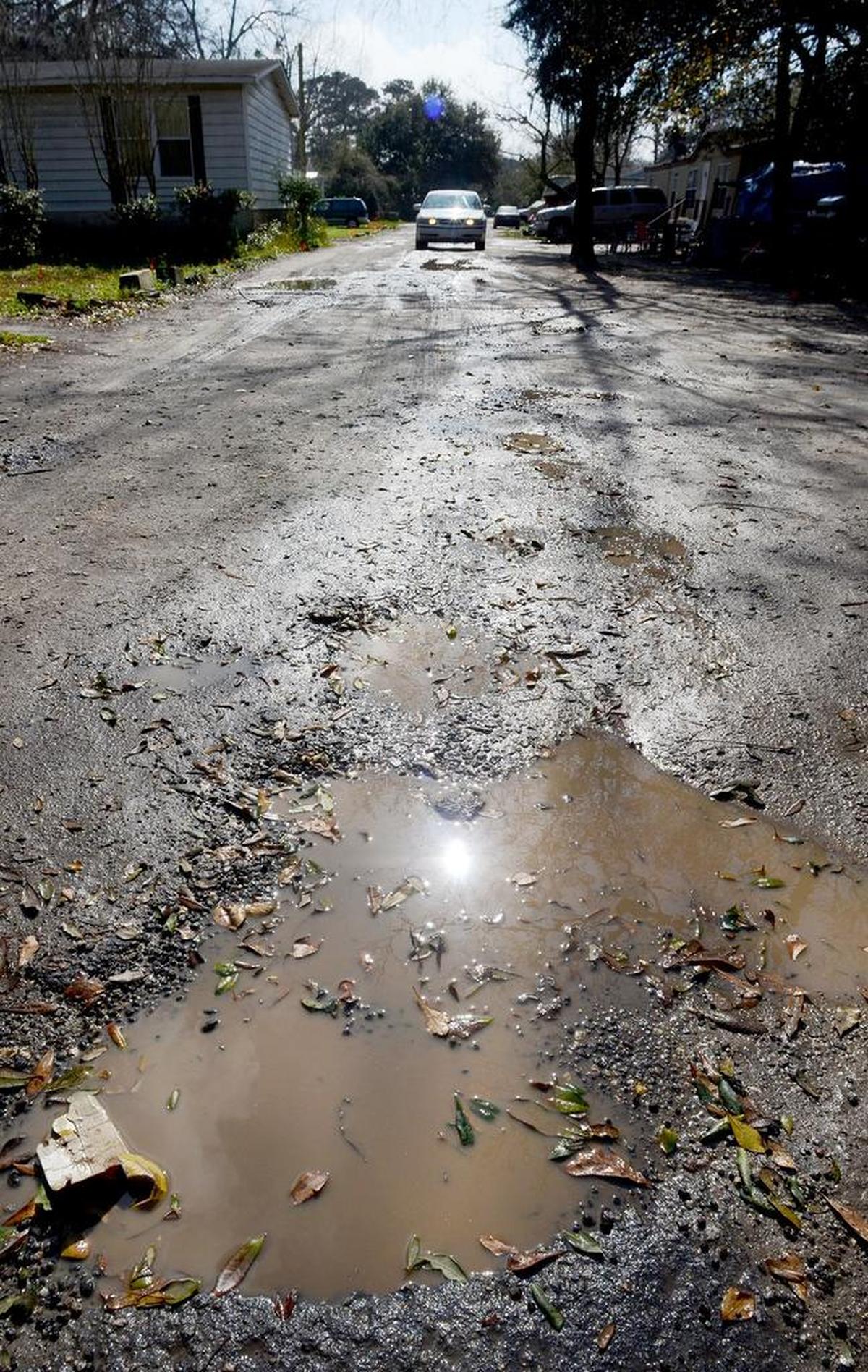 A car works its way down the pothole-ridden and puddle-filled Blazing Star Lane on Hilton Head Island in 2016.