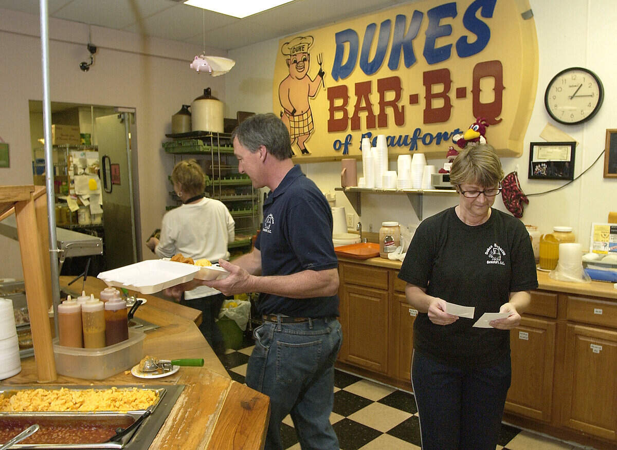 Jamie Harrelson, center, and wife Marlene, owners of Duke’s Barbecue fill take-out orders Friday afternoon. They will be closing their doors for good today.