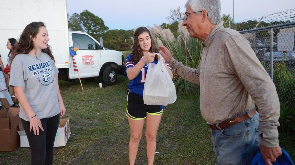 From right, Fred Corpuz drops off a food donation with Hilton Head Island High students McKara Johnston and Elizabeth Parker before the football game with Stall on Oct. 21, 2016. .